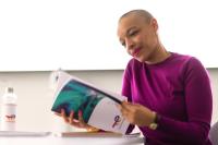 Employee alone in a meeting room in front of her laptop with notes sheets and water bottle