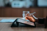 Vue de profil, gros plan d'une main féminine utilisant une tablette numérique avec un stylet