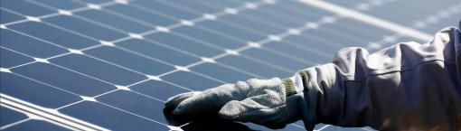 Gloved hand on a solar panel of the photovoltaic plant commissioned by ISE, Total and SunPower. Nanao, Japan.