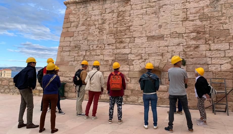 Group of people in front of a stone structure - see detailed description